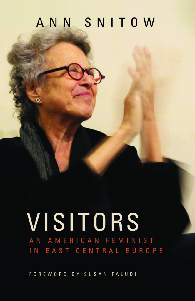 Cover of Visitors: An American Feminist in East Central Europe with a picture of Ann Snitow with short hair and circular, red glasses clapping her hands and smiling